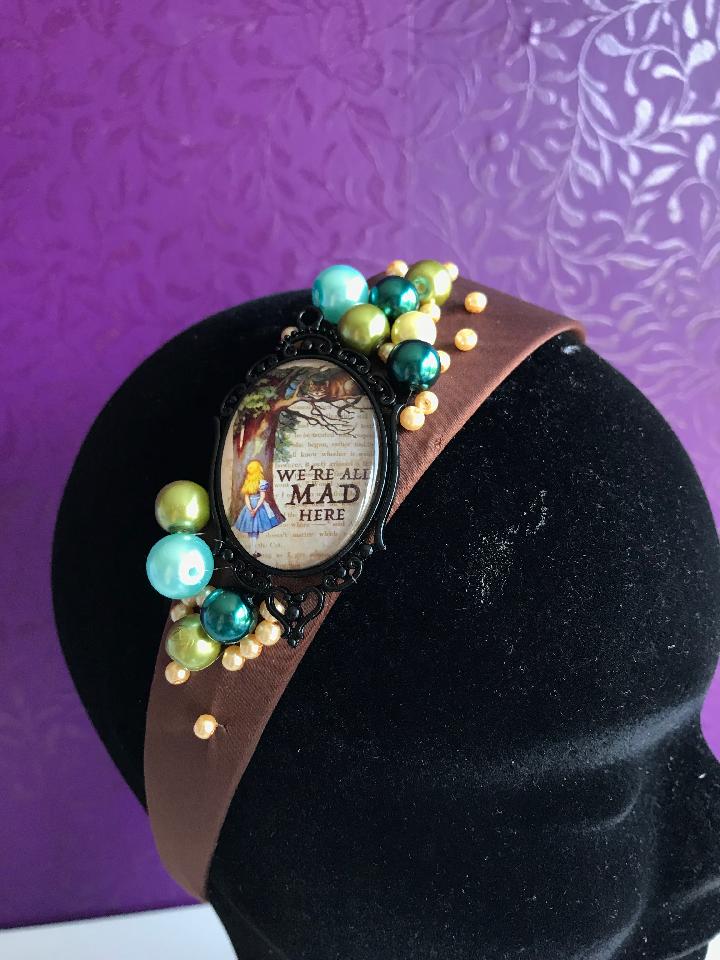 IMAGE - Brown satin headband with cameo featuring Alice and the Cheshire cat, finished with green, blue and cream pearls.