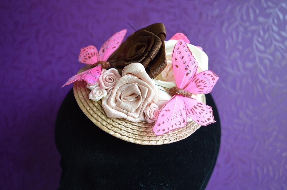 IMAGE - Light brown fascinator decorated with brown ribbon roses and pink butterflies.
