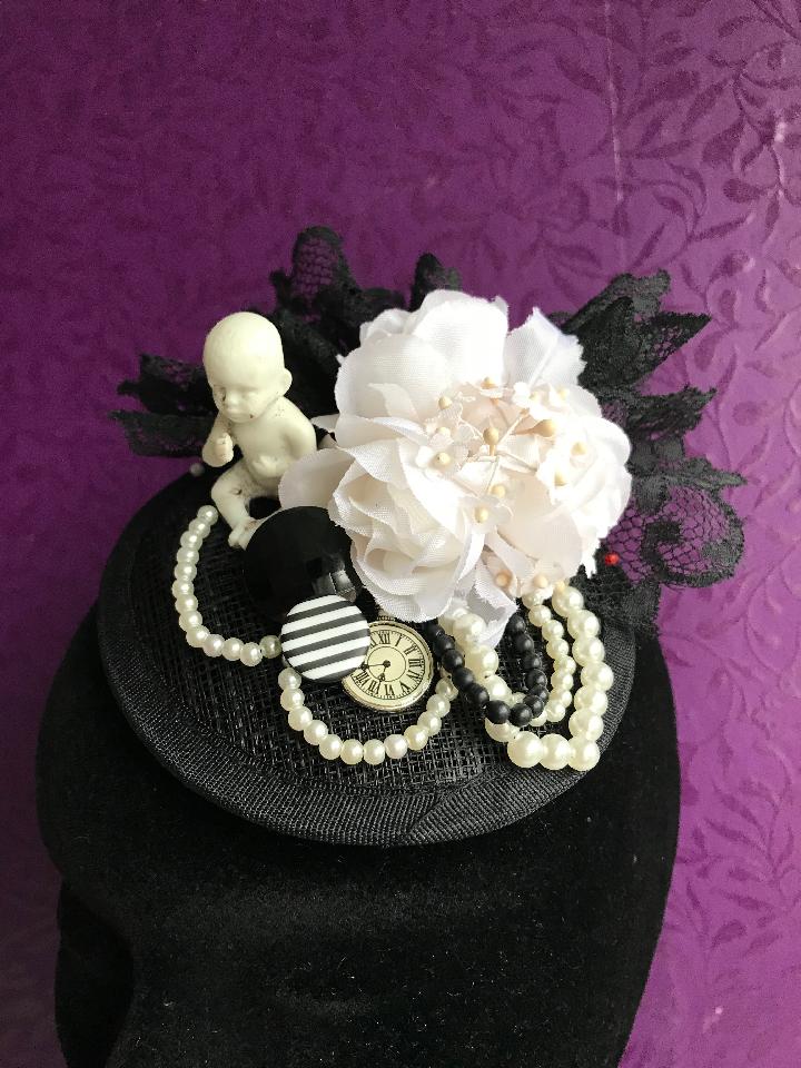 IMAGE - Black sinamay fascinator with antique porcelain doll, vintage black lace, vintage white flowers, buttons, clock charm and black and white pearls. Fixes to the hair with a comb.